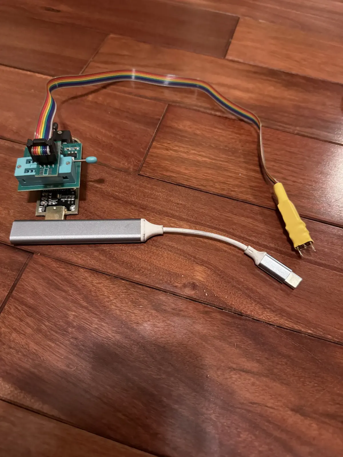 The full programming setup: a CH341A programmer on a green PCB, a 1.8V level-shifting adapter, the WSON8 probe, and a silver USB hub